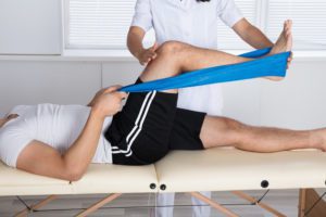 person receiving physical therapy exercise for leg, for treatments call our Schererville Pain Relief Doctors.