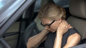Woman sitting in car holding neck feeling whiplash therapy in Crown Point is needed.