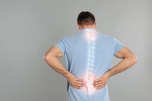 A man holding his back about to contact a Crown Point Back Pain Doctor